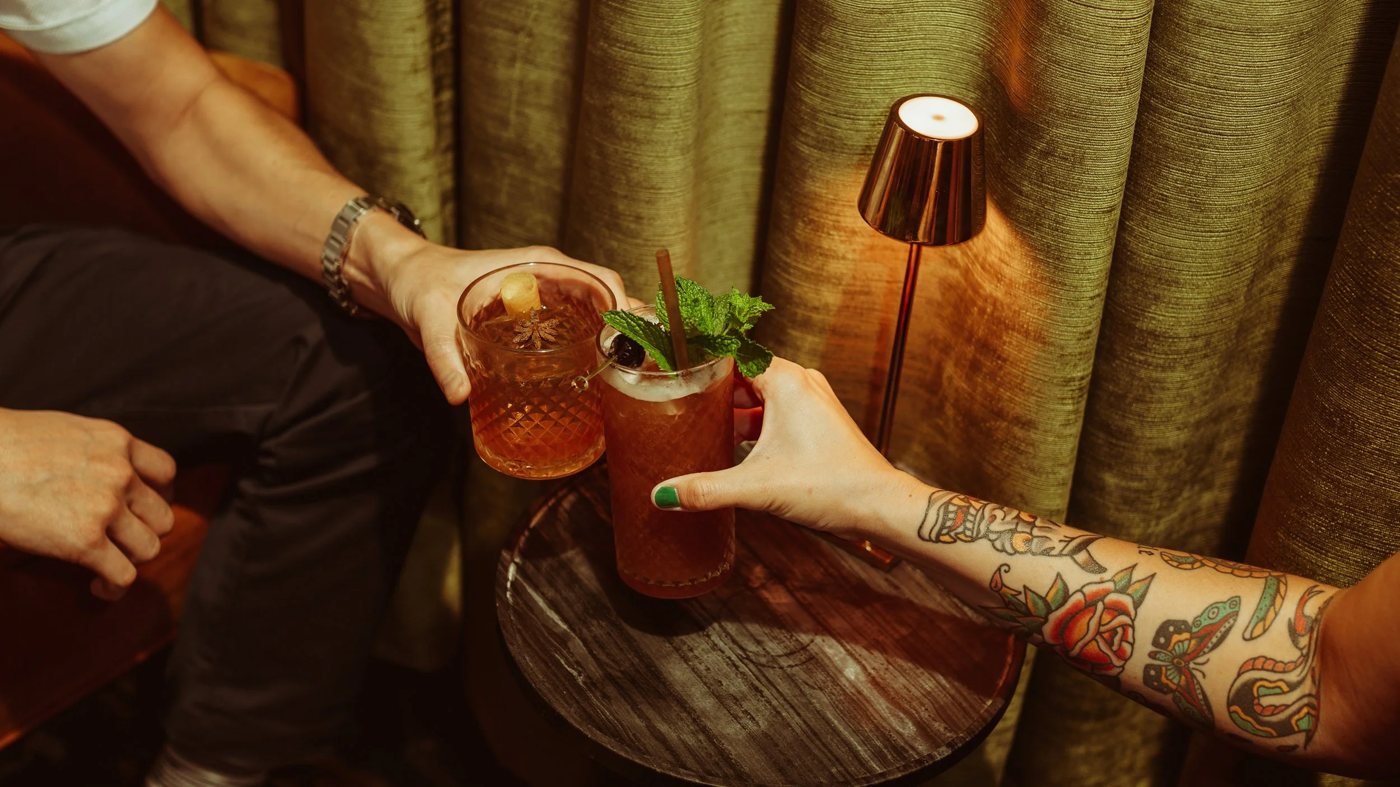 Guests holding cocktails at Green Lady Cocktail Room