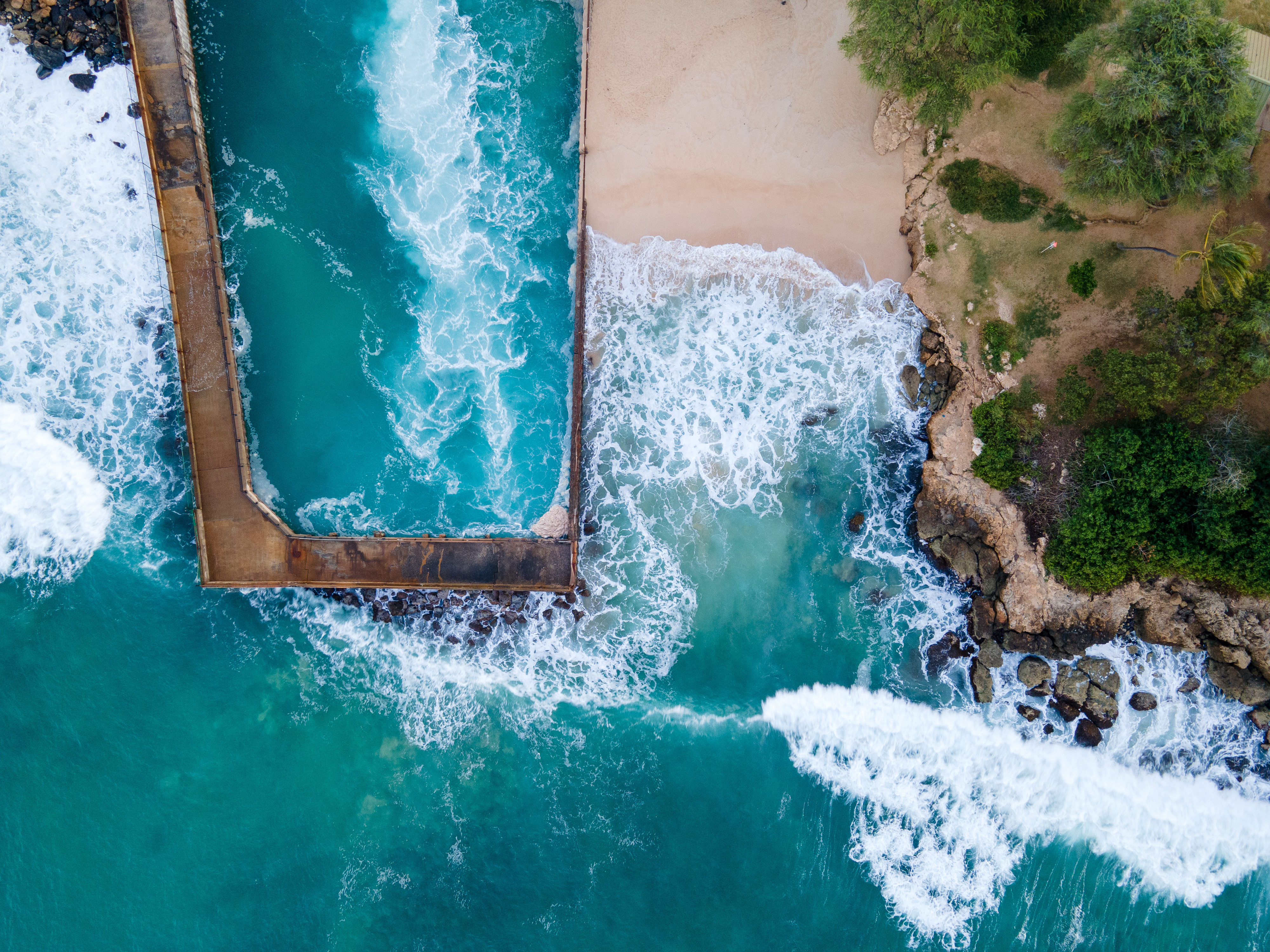 Aerial view of the shoreline and seawater channel at Electric Beach / Kahe Point Beach Park, Oʻahu