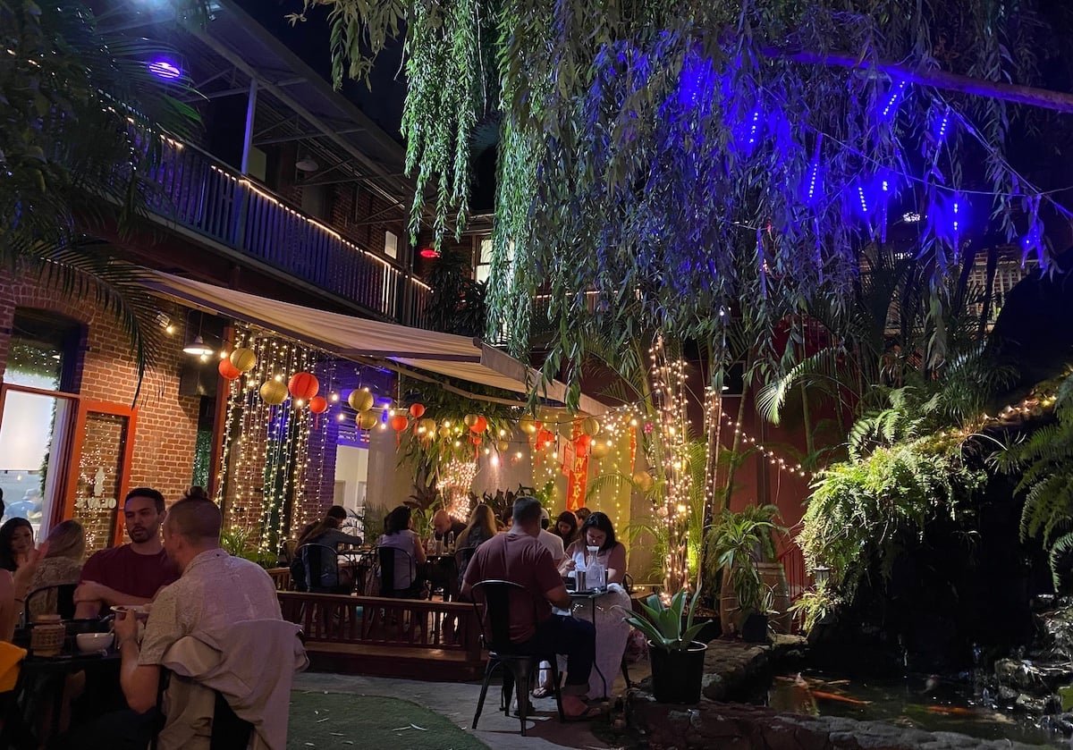 Olay’s outdoor courtyard at night with lanterns, string lights and a koi pond